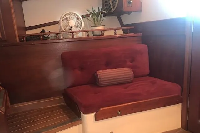 Slide: The Image of Cozy seating area in a 1986 Pilgrim 40 boat with red cushions and wooden accents. - 37