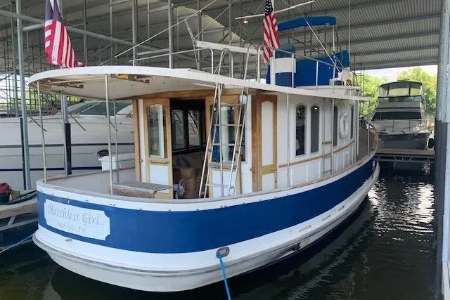 Slide: The Image of 1986 Pilgrim 40 boat docked under a covered marina with flags displayed. - 4