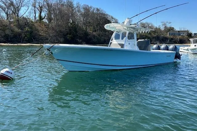Slide: The Image of 2015 Regulator 34 boat anchored in calm waters near a wooded shoreline. - 10