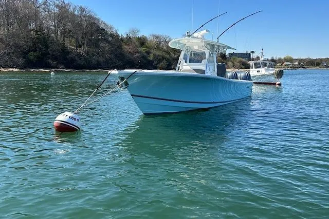 Slide: The Image of 2015 Regulator 34 boat anchored on calm water with fishing rods. - 11