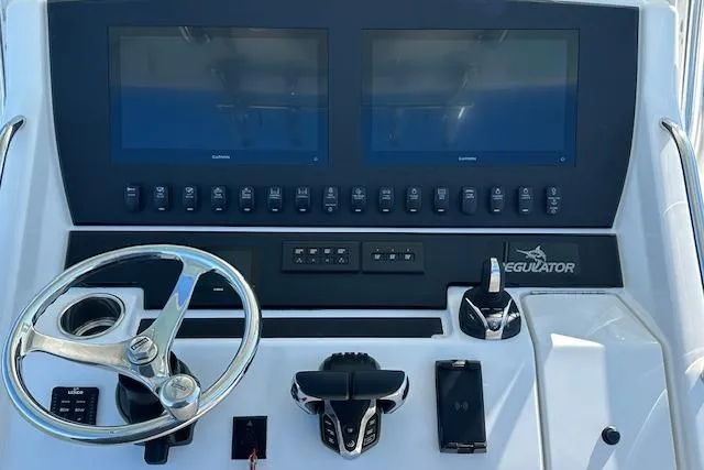 Slide: The Image of Control panel of a 2015 Regulator 34 boat with dual screens and steering wheel. - 15