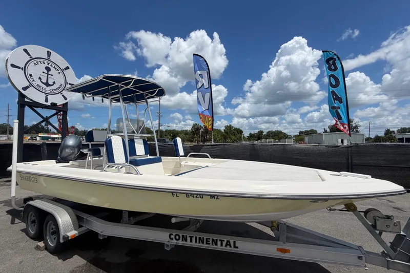 The Image of 2006 ShearWater 2200Z boat on trailer under blue sky with flags. - 0