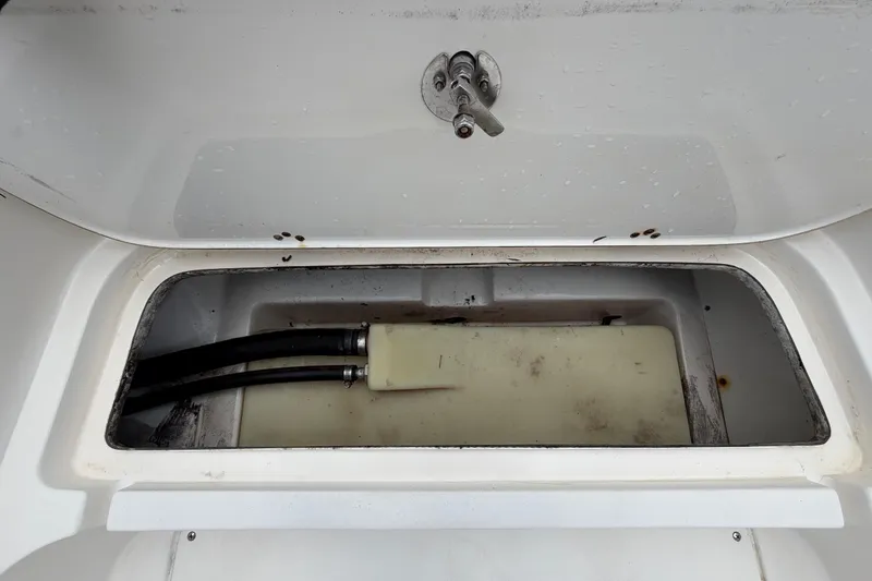 Slide: The Image of Open storage compartment in 2006 ShearWater 2200Z boat, showing hoses and tank. - 34