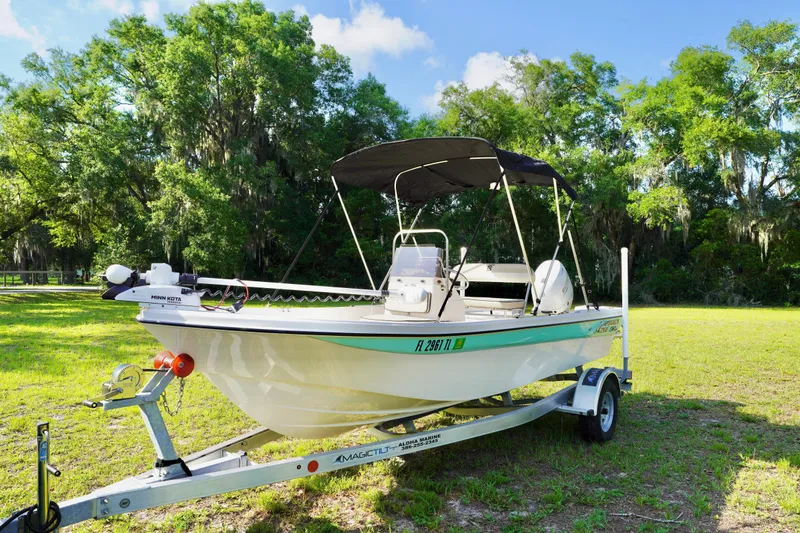 The Image of 2023 Carolina Skiff 178 JLS boat on trailer, parked on grassy area with trees. - 0