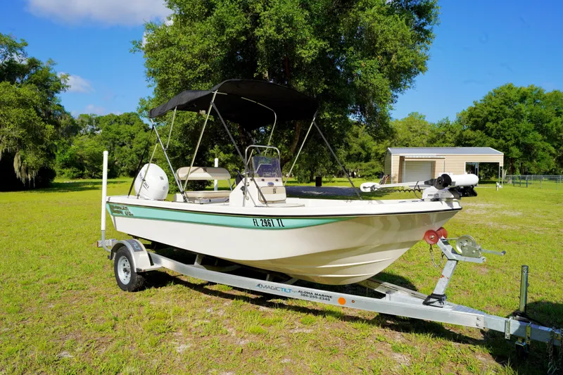 Slide: The Image of 2023 Carolina Skiff 178 JLS boat on trailer in grassy area with trees. - 1