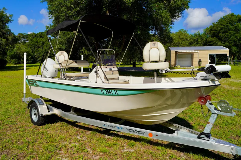 Slide: The Image of 2023 Carolina Skiff 178 JLS boat on trailer, parked on grass with trees in background. - 3