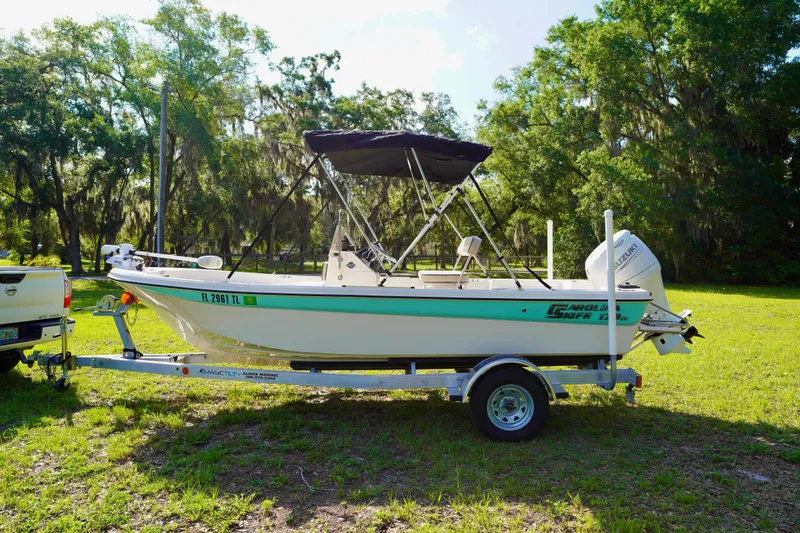 Slide: The Image of 2023 Carolina Skiff 178 JLS boat on trailer, parked in a grassy area with trees. - 4