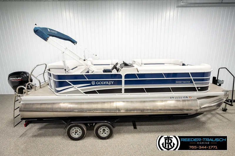 The Image of 2022 Godfrey Sweetwater 2286 pontoon boat with Mercury engine on trailer in showroom. - 1