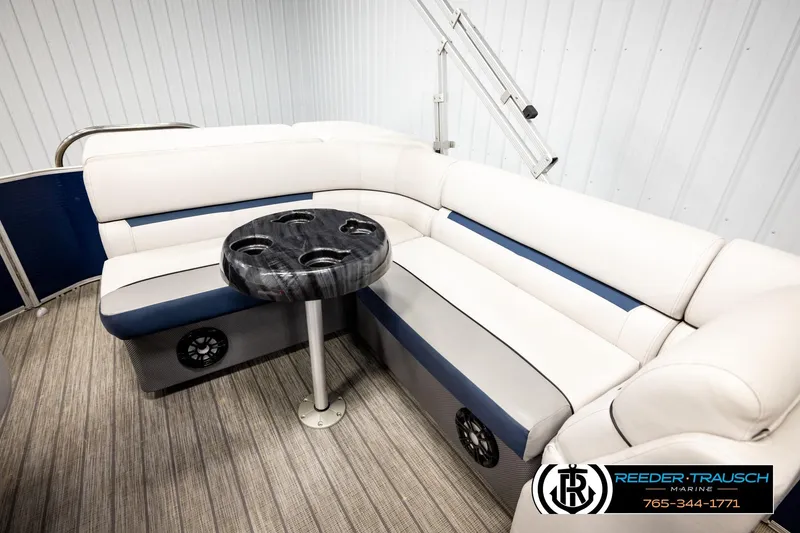 Slide: The Image of 2022 Godfrey Sweetwater 2286 boat interior with white and blue seating and a round table. - 22
