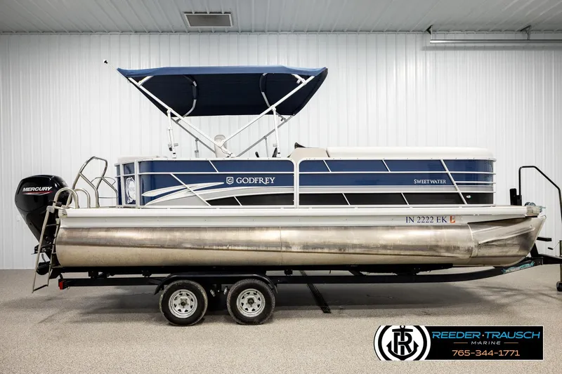 Slide: The Image of 2022 Godfrey Sweetwater 2286 pontoon boat with blue canopy and Mercury engine in showroom. - 5