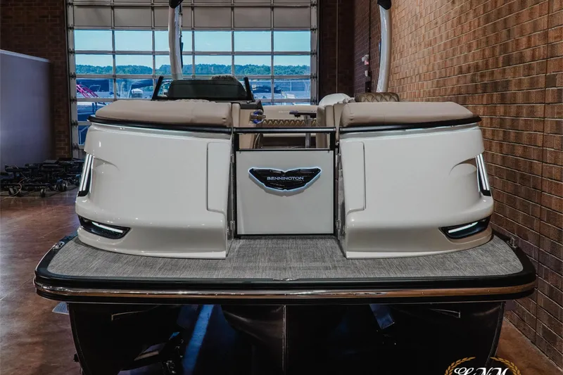 Slide: The Image of 2026 Bennington 27QXSBAT2 pontoon boat in showroom, rear view with sleek design. - 4