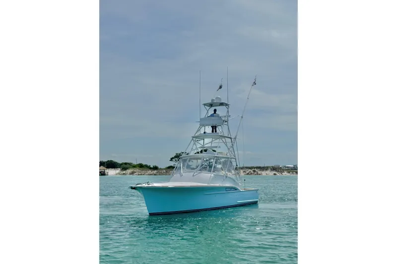 Slide: The Image of 2006 Miller Marine 36 boat on clear blue water with a tower and flags. - 2
