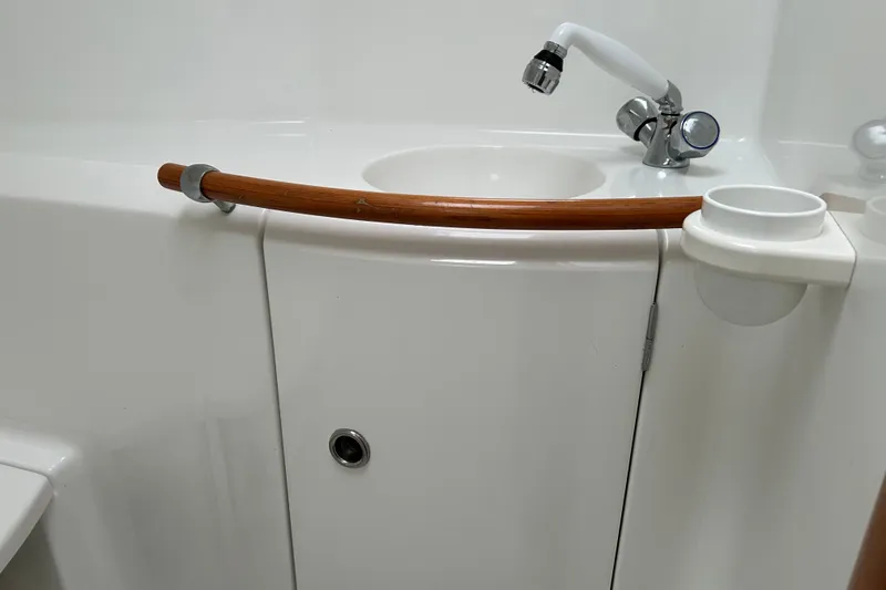 Slide: The Image of Bathroom sink area on a 1998 Beneteau 411 yacht, featuring a faucet and wooden rail. - 12