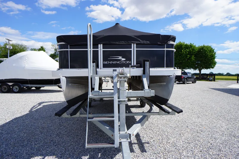 Slide: The Image of 2023 Bennington S 18 Fishing boat on trailer, parked outdoors under blue sky. - 7