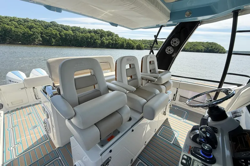 Slide: The Image of 2021 Boston Whaler 420 Outrage interior with luxurious seating and modern controls on a scenic lake. - 18