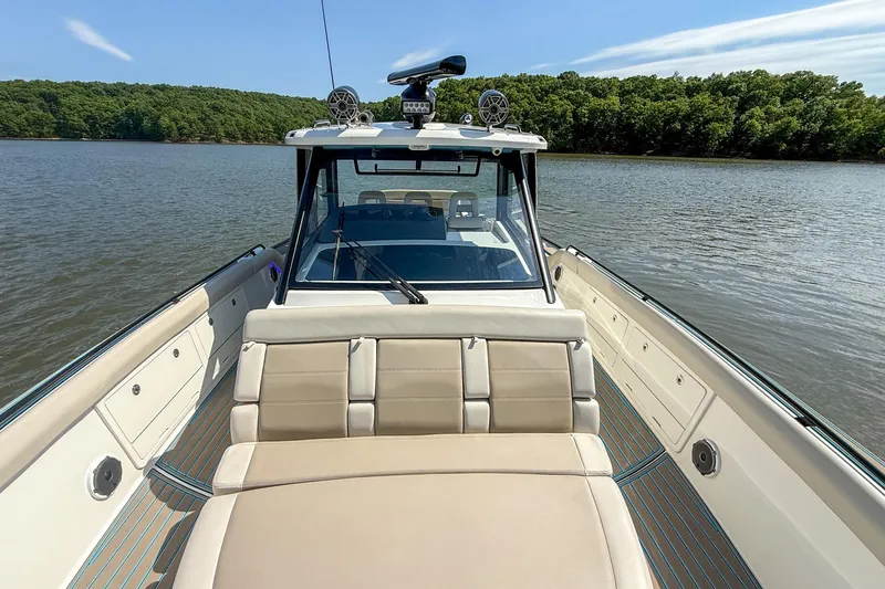 Slide: The Image of 2021 Boston Whaler 420 Outrage boat on calm lake with lush green shoreline. - 26