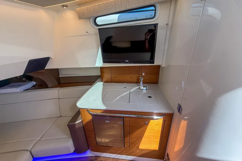 Slide: The Image of Interior of 2021 Boston Whaler 420 Outrage, featuring a compact kitchenette and seating area. - 35