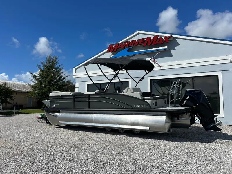 Slide: The Image of A 2027 Harris Cruiser 230 pontoon boat is parked on gravel in front of a building with a MarineMax logo. - 3