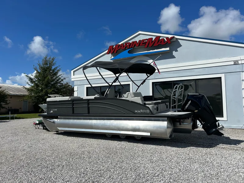 Slide: The Image of A 2027 Harris Cruiser 230 pontoon boat is parked on gravel in front of a building with a MarineMax logo. - 4