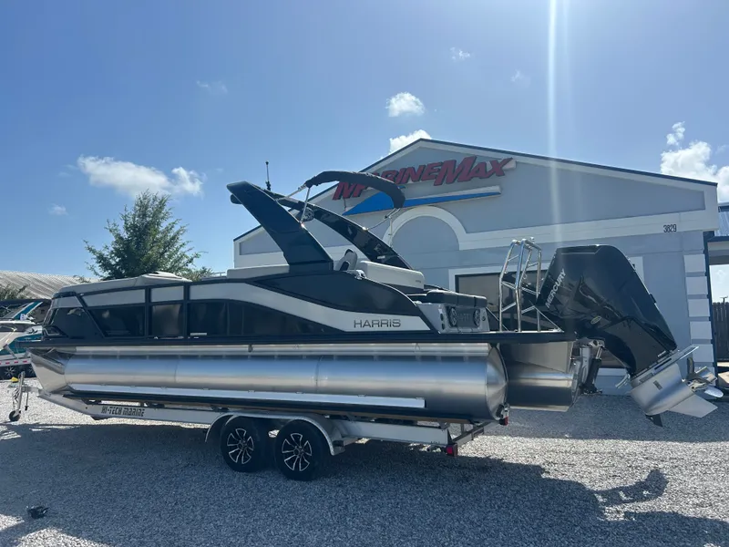Slide: The Image of A modern pontoon boat with dual outboard engines sits on a trailer in front of a building. - 10