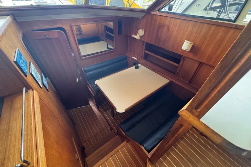 Slide: The Image of 1987 Chris-Craft 44 Commander interior with wooden dining area and cushioned seating. - 11