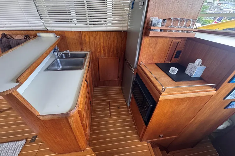 Slide: The Image of 1987 Chris-Craft 44 Commander yacht kitchen with wood cabinetry, sink, and appliances. - 12