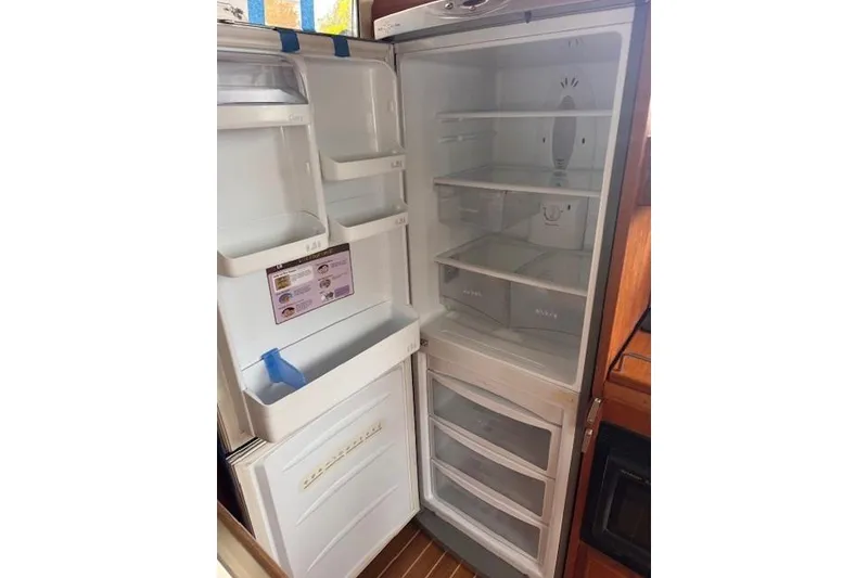 Slide: The Image of Open refrigerator inside 1987 Chris-Craft 44 Commander yacht, showcasing spacious interior shelves. - 13