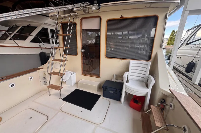 Slide: The Image of 1987 Chris-Craft 44 Commander yacht deck with ladder, chairs, and dockside view. - 2