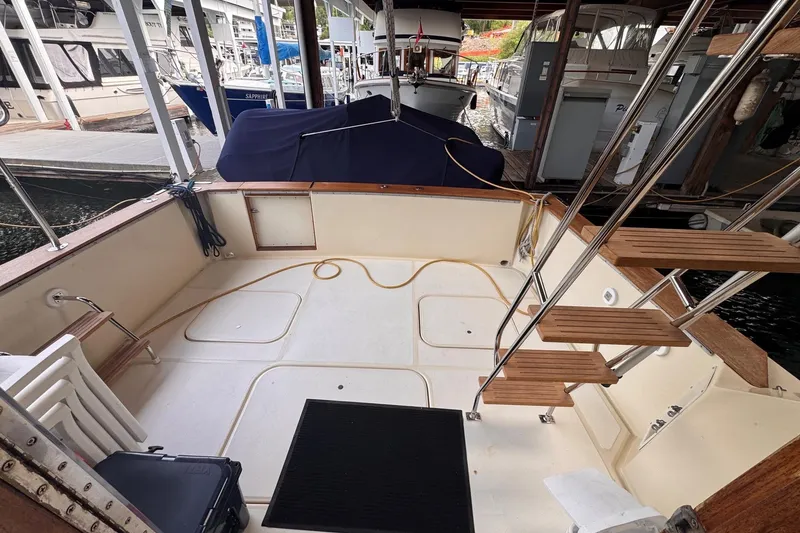 Slide: The Image of 1987 Chris-Craft 44 Commander boat deck with wooden steps and docked surroundings. - 3