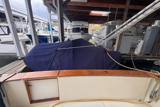 Slide: The Image of 1987 Chris-Craft 44 Commander docked under a covered marina, partially covered with a blue tarp. - 5