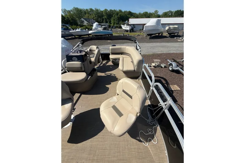 Slide: The Image of 2021 Sun Tracker Bass Buggy 16 XL Select pontoon boat with beige seating, parked outdoors. - 13