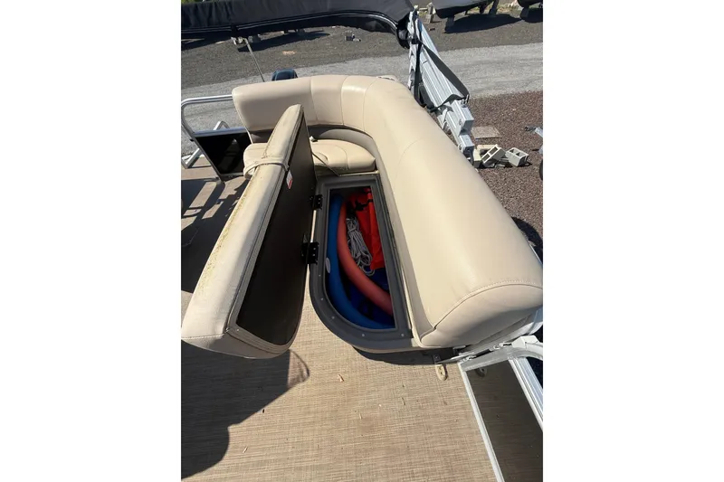 Slide: The Image of 2021 Sun Tracker Bass Buggy 16 XL Select with open storage compartment under beige seating. - 23