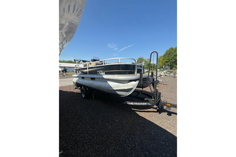 Slide: The Image of 2021 Sun Tracker Bass Buggy 16 XL Select pontoon boat on trailer, parked outdoors. - 4