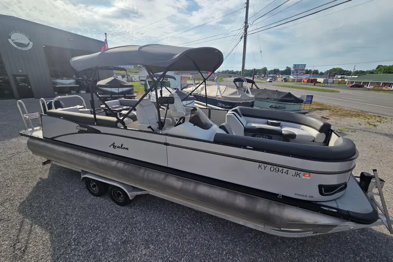 Slide: The Image of 2021 Avalon 2585 Catalina QL pontoon boat parked on gravel lot near dealership. - 2