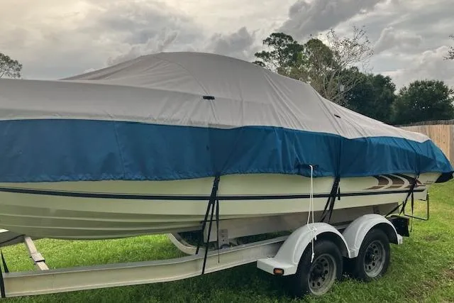 The Image of 1998 Sea Ray 210 Bow Rider boat covered on trailer, parked on grass. - 1
