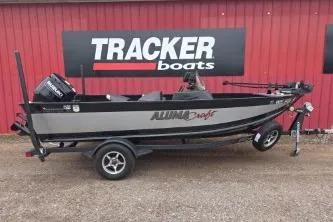 Slide: The Image of 2022 Alumacraft Competitor 165 SC boat on trailer, parked by Tracker Boats sign. - 2