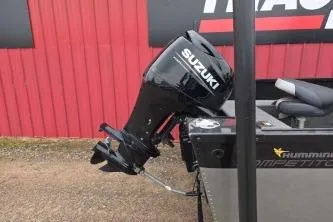 Slide: The Image of 2022 Alumacraft Competitor 165 SC with Suzuki outboard motor, parked near a red building. - 9