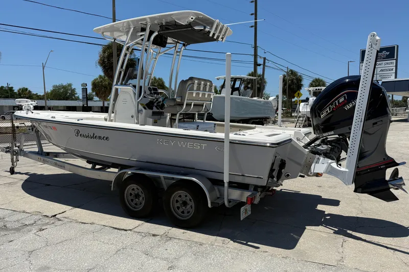 Slide: The Image of 2024 Key West 230 Bay Reef boat on trailer, featuring a powerful outboard motor. - 2