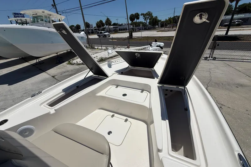 Slide: The Image of 2024 Key West 230 Bay Reef boat with open storage compartments, docked outdoors. - 8