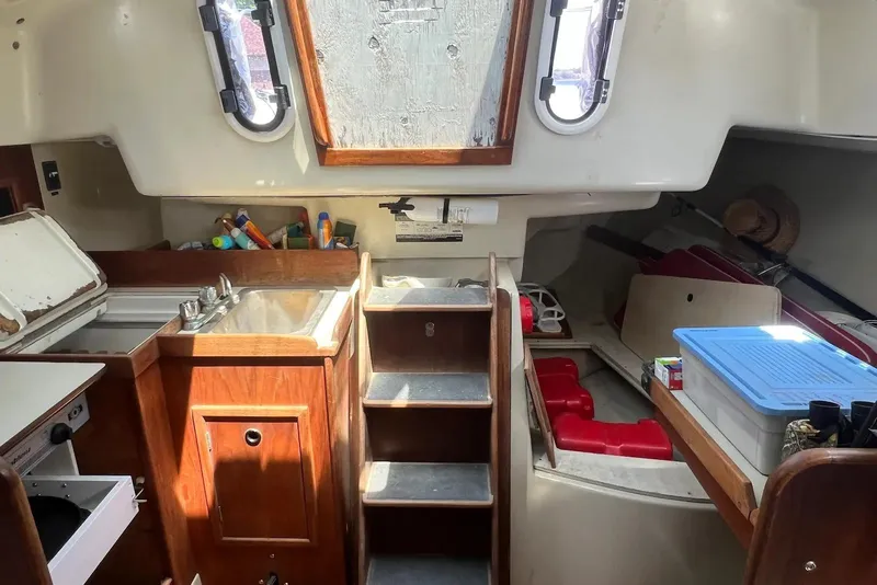 Slide: The Image of Interior of a 1981 C&C 34 sailboat featuring a compact kitchen and storage area. - 12