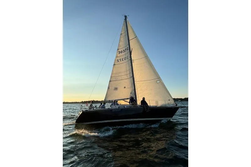 The Image of 1981 C&C 34 sailboat gliding on water at sunset with full sails. - 5
