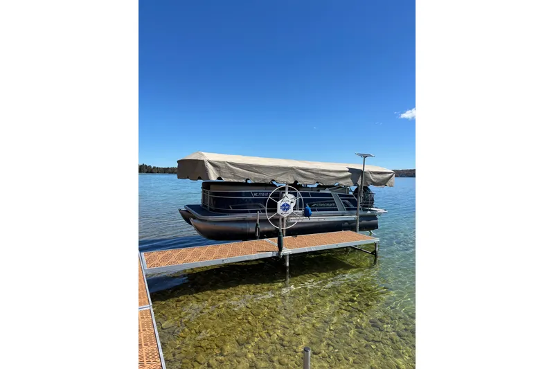The Image of 2022 Starcraft EX 22 Q pontoon boat docked on clear lake under blue sky. - 0