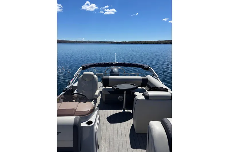 Slide: The Image of 2022 Starcraft EX 22 Q pontoon boat on a serene lake under clear blue skies. - 11
