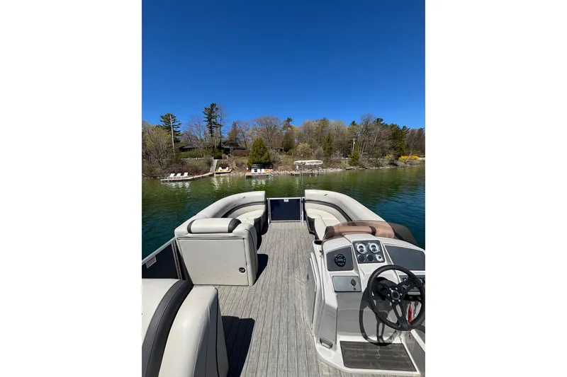 Slide: The Image of 2022 Starcraft EX 22 Q pontoon boat on a serene lake with wooded shoreline. - 12