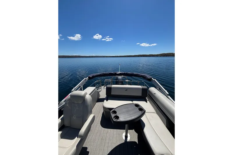 Slide: The Image of 2022 Starcraft EX 22 Q pontoon boat on a serene lake under clear blue skies. - 14