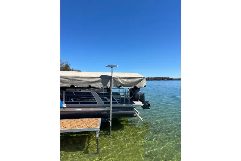 Slide: The Image of 2022 Starcraft EX 22 Q pontoon boat docked on clear lake under blue sky. - 2