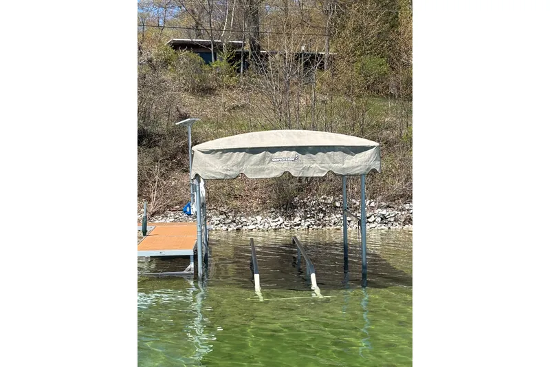 Slide: The Image of Boat lift with canopy on a lake, surrounded by trees and rocky shoreline. - 3