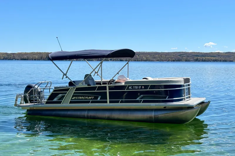 Slide: The Image of 2022 Starcraft EX 22 Q pontoon boat on a serene lake under clear skies. - 4