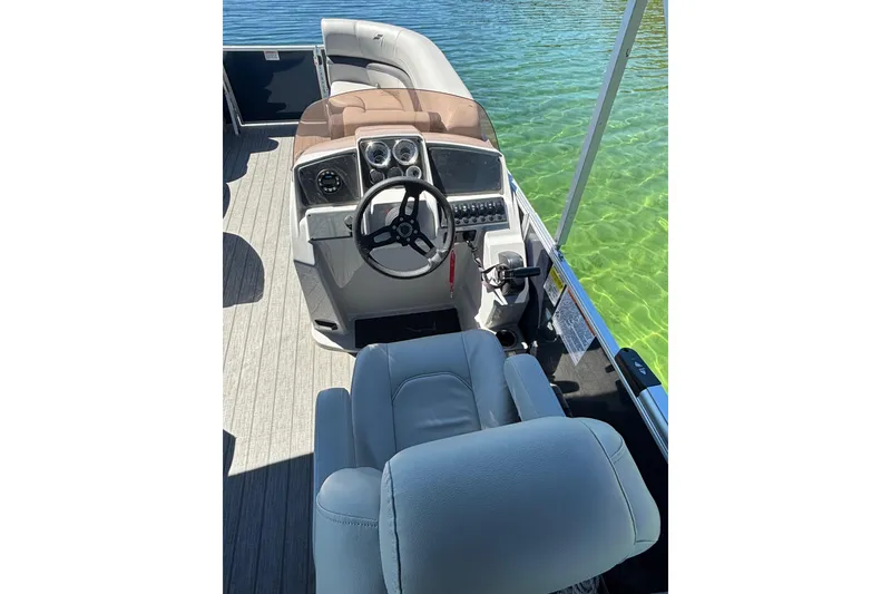 Slide: The Image of 2022 Starcraft EX 22 Q boat interior with steering wheel and seating on clear water. - 6