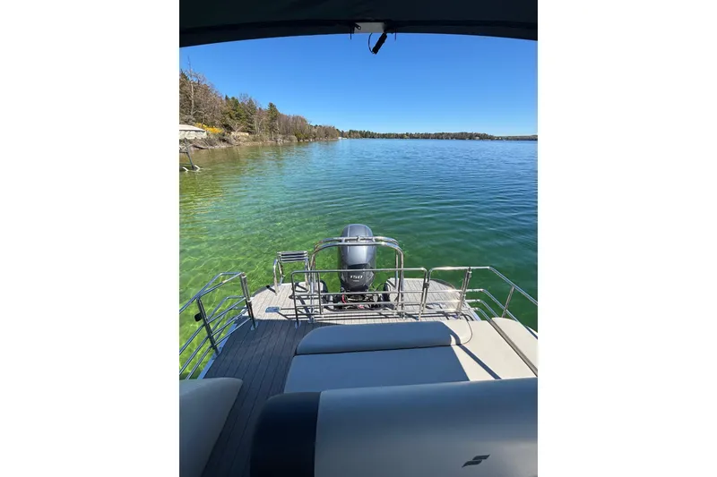 Slide: The Image of 2022 Starcraft EX 22 Q pontoon boat on a serene lake with clear blue water. - 8
